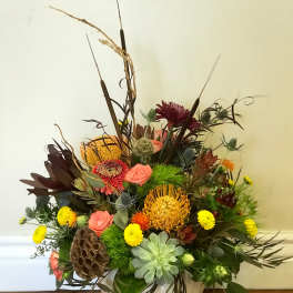 Mixed floral arrangement in a white bowl vase with tall dried accents