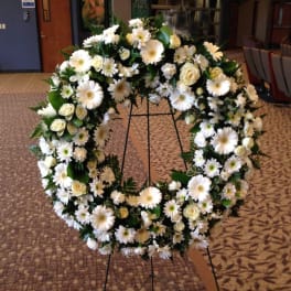 White floral wreath on a black stand