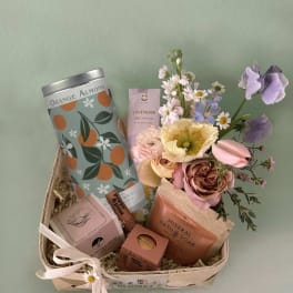 Gift basket with flowers, bath items, and a ribbon bow