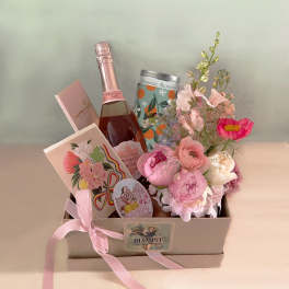 Gift box with pink flowers, a rosé bottle, and chocolates