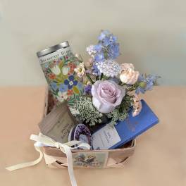 Gift basket with pastel flowers, tea, soap, and chocolate