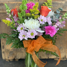 Mixed bouquet in a glass vase with orange ribbon