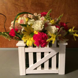 Mixed bouquet in a white wooden crate with yellow, white, and pink flowers