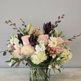 Pink roses and white blooms arranged in a square glass vase