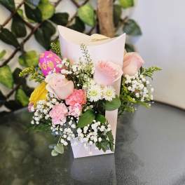 Small bouquet of pink roses, white daisies, and baby’s breath in a paper sleeve