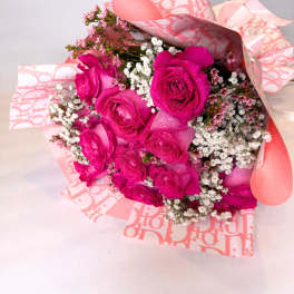 Bouquet of hot pink roses with white filler flowers in pink wrapping