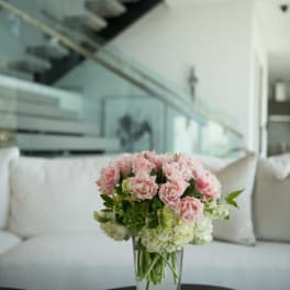 Pink and white flowers arranged in a clear glass vase