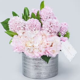 Pink hydrangeas and lilies arranged in a silver textured vase
