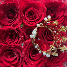 Red roses in a clear box with a gold butterfly ornament