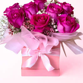 Pink roses arranged in a pink gift box with a ribbon