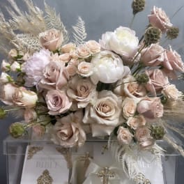 Blush and white rose arrangement above decorated white Bibles and a candle