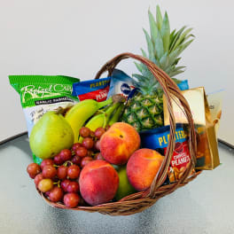 Fruit basket with grapes, peaches, pear, pineapple, bananas, and snack bags