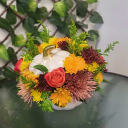 Pumpkin-shaped floral arrangement with a white pumpkin and mixed autumn flowers