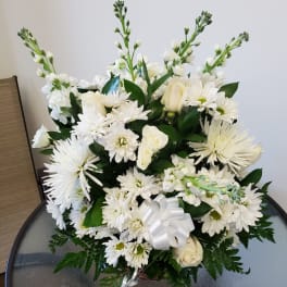White floral arrangement with daisies and roses in a basket