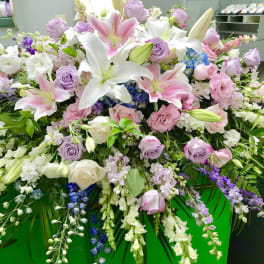 Large pastel floral arrangement with lilies, roses, and cascading blooms