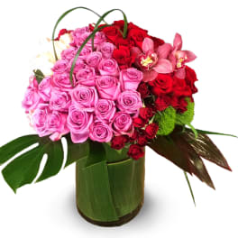 Bouquet of pink and red roses with orchids in a wrapped vase