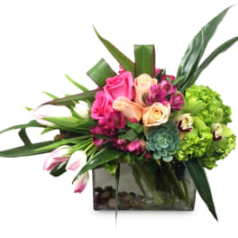 Mixed bouquet of roses, tulips, and green hydrangeas in a glass vase