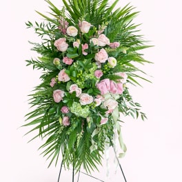 Standing floral spray with pink roses and greenery on a metal easel