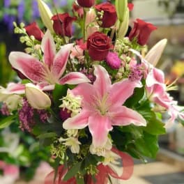 Bouquet of pink lilies and red roses tied with a ribbon