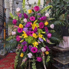 Large standing floral spray with pink, yellow, and green blooms