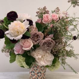 Mixed pink and cream floral arrangement in a patterned vase