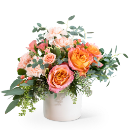 Peach and pink roses with pale carnations in a white vase