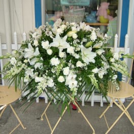 Large white floral arrangement with lilies and roses on a stand