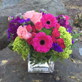Pink and purple mixed bouquet in a clear square vase