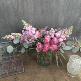 Pink rose and lavender flower arrangement in a glass vase