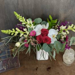 Arrangement of red roses and white orchids in a white vase