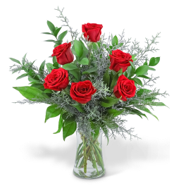 Red roses arranged in a clear glass vase with silver foliage