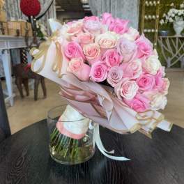 Bouquet of pink and white roses wrapped in pale paper