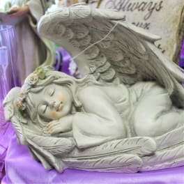 Sleeping angel figurine with large wings on a purple cloth