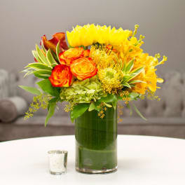 Bright yellow and orange floral arrangement in a tall glass vase