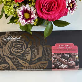 Bouquet above a box of assorted chocolates