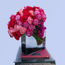 Bouquet of red, pink, and purple roses in a clear glass vase
