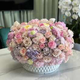 Large pastel bouquet of roses and hydrangeas in a white textured vase