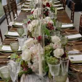 Long banquet table with white and red floral centerpieces in glass vases