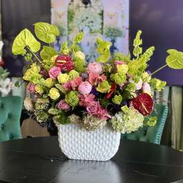 Mixed pink and green floral arrangement in a white textured vase