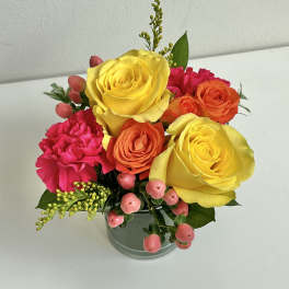 Bouquet of yellow, orange, and pink flowers in a glass vase