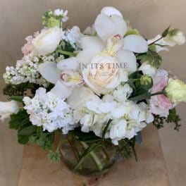 White and pale pink floral arrangement in a glass vase
