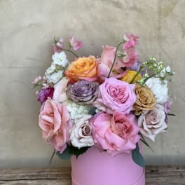 Pink and peach roses arranged in a round pink box