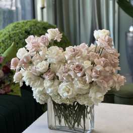 Blush and white roses arranged in a clear rectangular vase