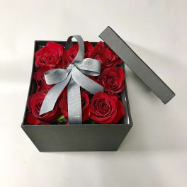 Red roses in a black gift box with a gray ribbon bow