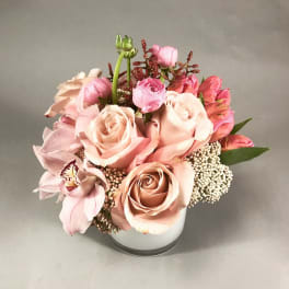 Pink and peach roses with orchids arranged in a white vase
