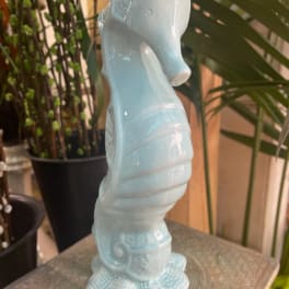 Light blue ceramic seahorse figurine on a table