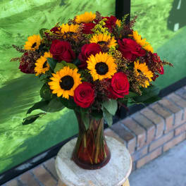 Bouquet of red roses and yellow sunflowers in a glass vase