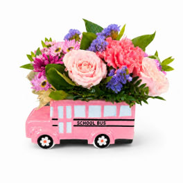 Pink floral arrangement in a pink school bus container