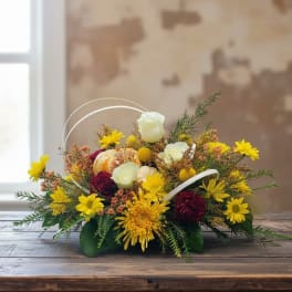 Low basket arrangement with yellow and white flowers and a small pumpkin