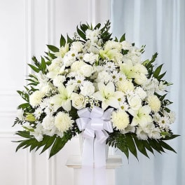 White floral standing spray with lilies, roses, and chrysanthemums on a pedestal